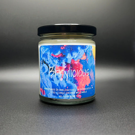 Elysium Candle Co.’s Brrylicious candle, featuring a vibrant blue and red abstract label, hand-poured with a 7 oz coconut soy wax blend and 40-50 hour burn time.