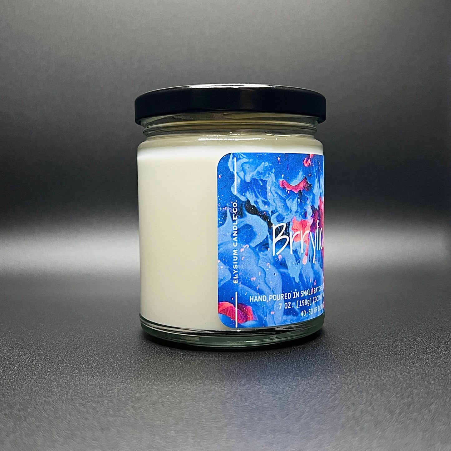 Side view of Elysium Candle Co.’s Brrylicious candle, showcasing a creamy coconut soy wax and an eye-catching, colorful abstract design on the label.