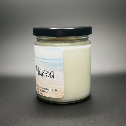 Elysium Candle Co.’s Butt Naked candle showing a front-facing label with a beach view, representing the relaxing scent made from coconut soy wax.