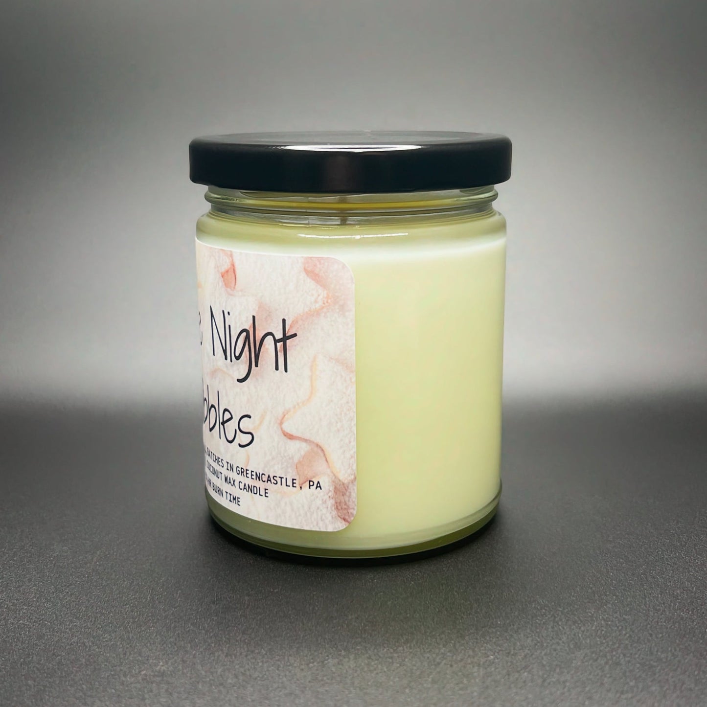 Front view of Elysium Candle Co.’s Late Night Nibbles, featuring an artistic snack-themed label on the coconut soy wax blend jar candle.