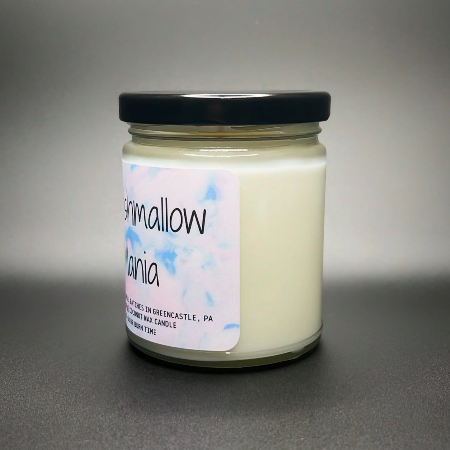 A premium Marshmallow Mania candle from Elysium Candle Co. with a hand-poured coconut soy wax blend in a jar, detailed with a softly hued, artistic label.