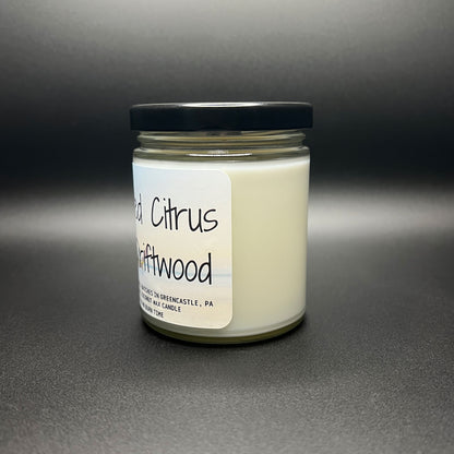 Angled view of the Salted Citrus and Driftwood coconut wax candle, with emphasis on the label that bears the Elysium Candle Co. branding and the beach-inspired artwork, indicating its handcrafted nature and burn time.